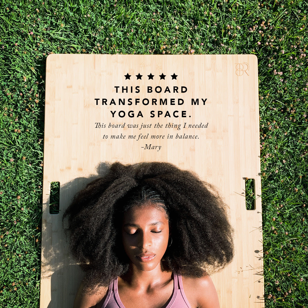 Woman in Shavasana on The Root Board on grass in the park.