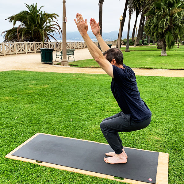 Man in chair pose on Root Board on the Ocean Park grass in Santa Monica, CA 