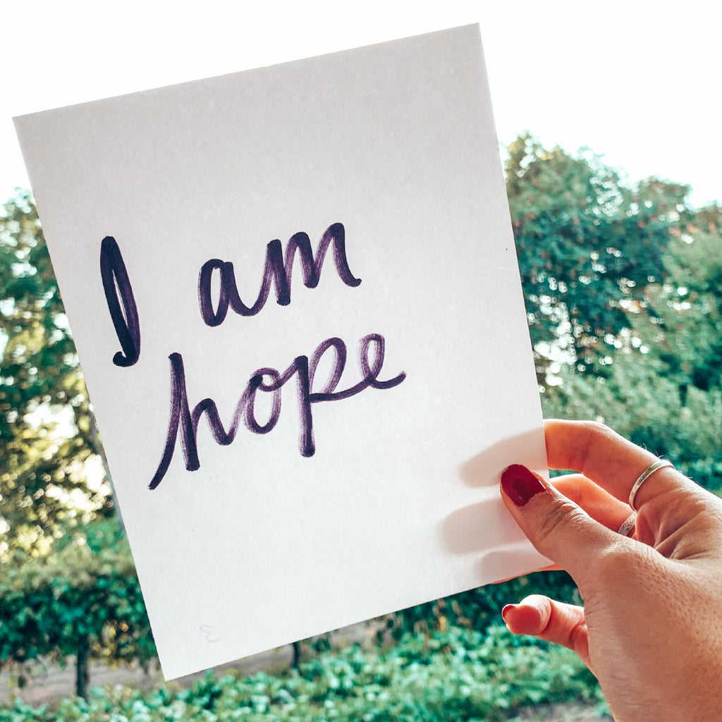 hand holding card that reads, "I am hope"