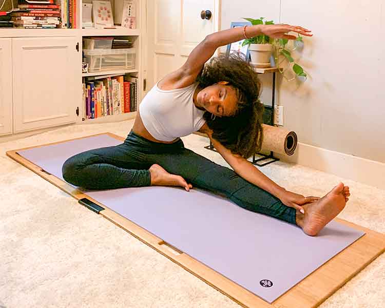 Woman practicing yoga on a carpeted floor using a yoga board for stability